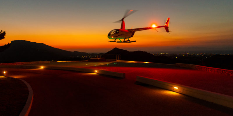 A helicopter landing at the "Touch of Class" Villa in Rhodes at dusk. Greece Sotheby's International Realty