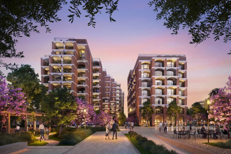 FIX Residences Thessaloniki: landscaped promenade between the two brick residential buildings at dusk, with blossoming trees